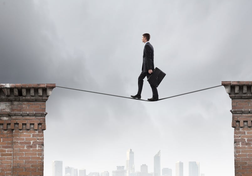 Lawyer walking on tightrope as a metaphor for avoiding contract risk.