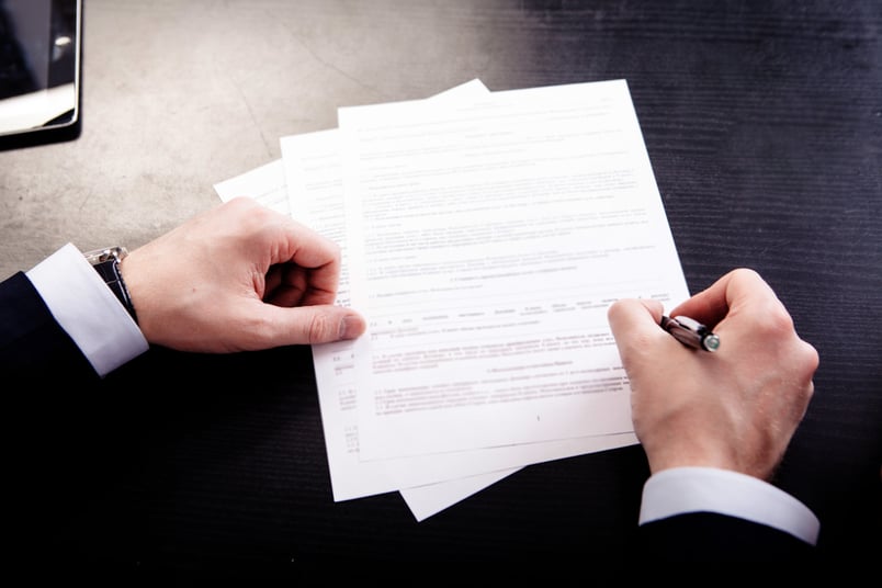 Lawyer writing on contract by hand, showing the old way of how to redline a contract.